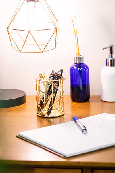 ADD-and-ADHD-can-lead-to-significant-challenges A cup full of pens sits on a desk under a lamp. A clipboard with paperwork lays next to it.