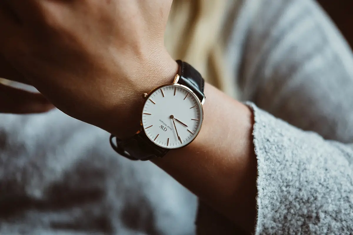 Can You Develop ADHD as an Adult? Close-up of a person’s wrist wearing a minimalist analog watch with a white face and black leather strap. The person appears to be checking the time, and the background is softly blurred, creating a calm, focused aesthetic.