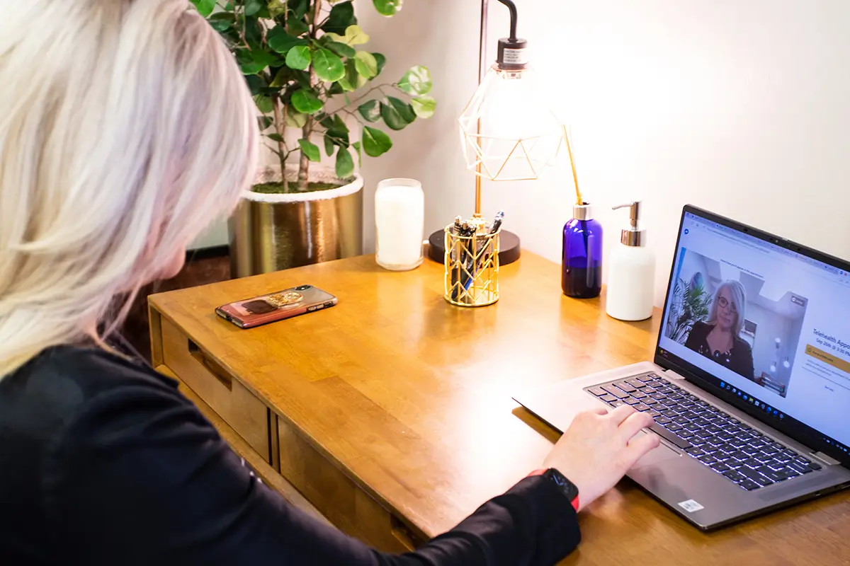 Person attending an online therapy session on a laptop.